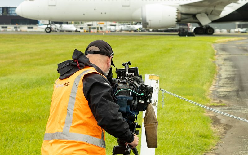 Picture of a news media camera operator photographing a plane arriving at Auckland Airport